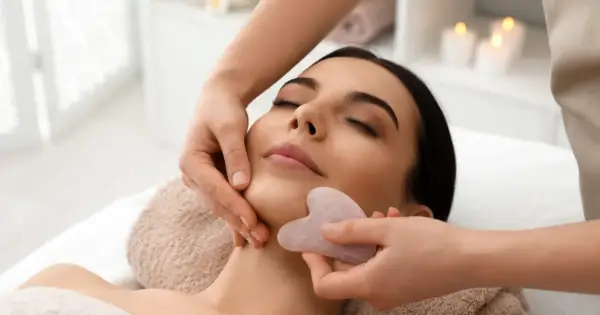 Relaksacyjny masaż twarzy kamieniem gua sha. Delikatne ruchy kamienia poprawiają krążenie i odmładzają skórę.